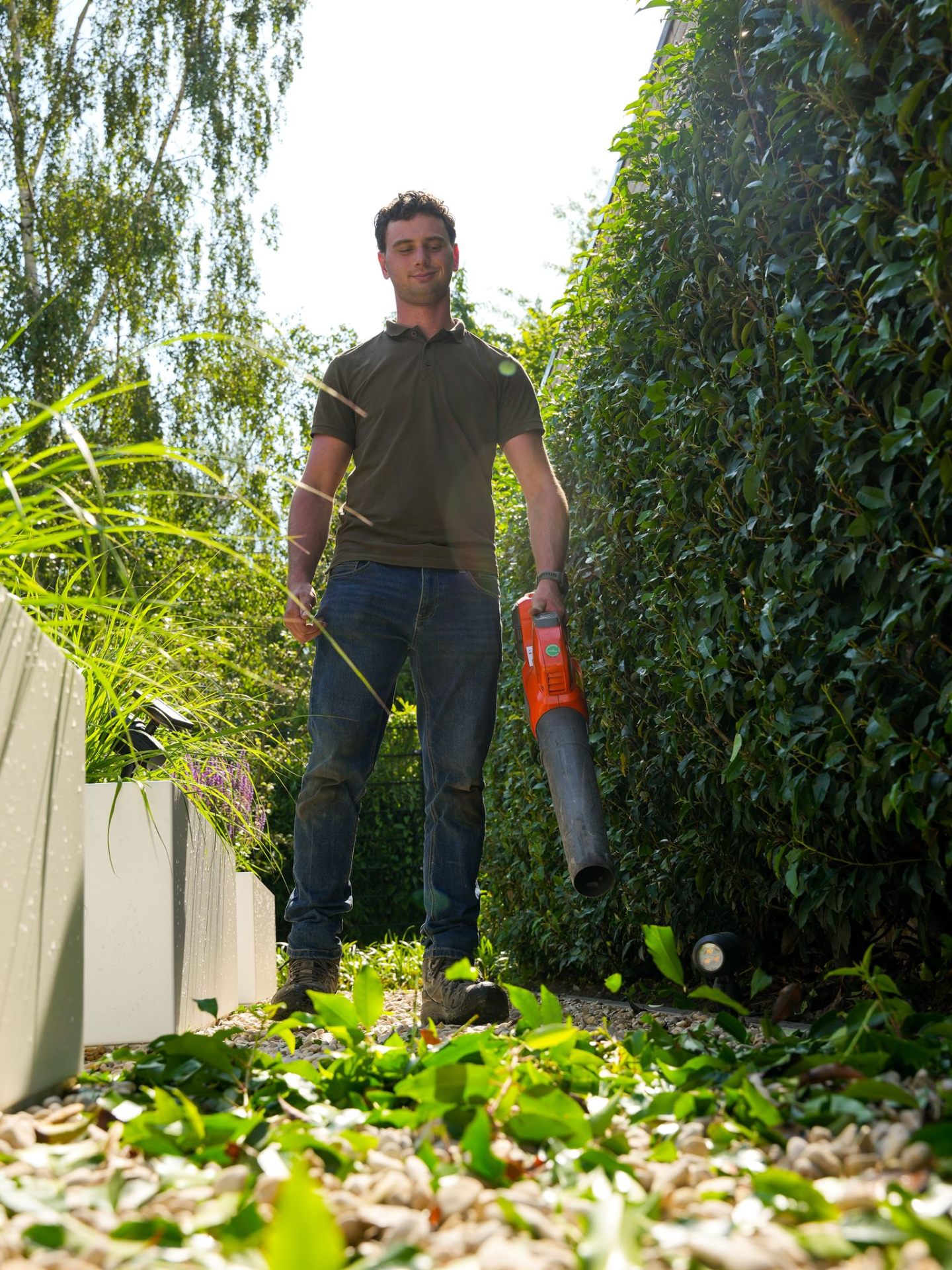 Hovenier met bladblazer tussen de beplanting